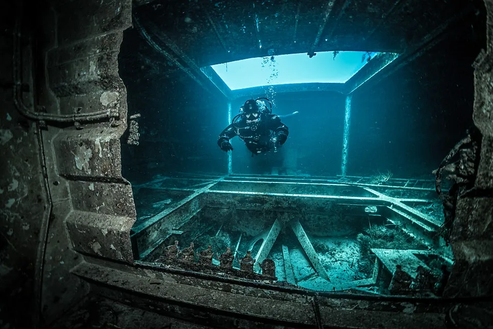 Advanced Open Water Diver practising underwater navigation inside a structure, holding position with neutral buoyancy