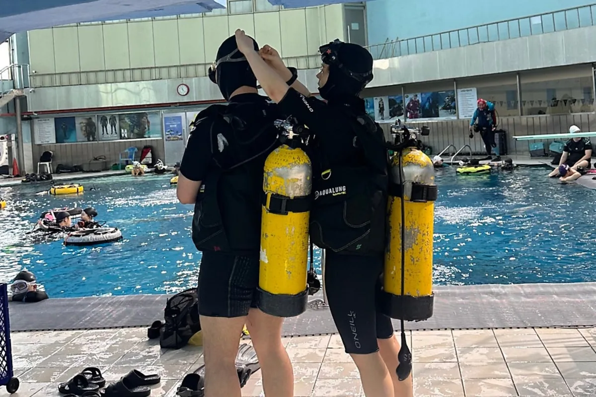 Two divers running a BWRAF pre-dive safety check together at the poolside during diver essentials course training