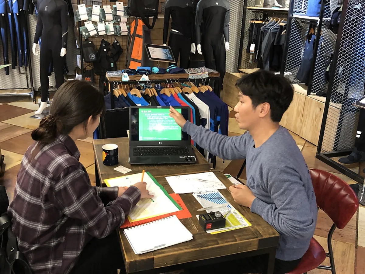 Instructor and prospective student reviewing a scuba course schedule and pricing together at NB Divers in Seoul