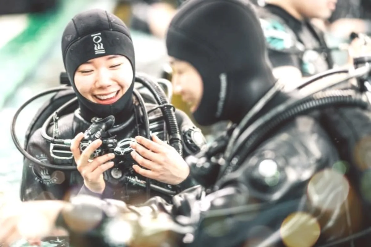 Instructor and diver reviewing scuba equipment closely together before a PADI ReActivate refresher session