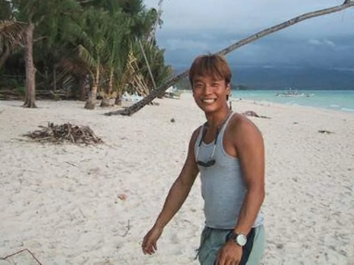 A young Charlie Jung walking along an untouched tropical beach early in his diving career