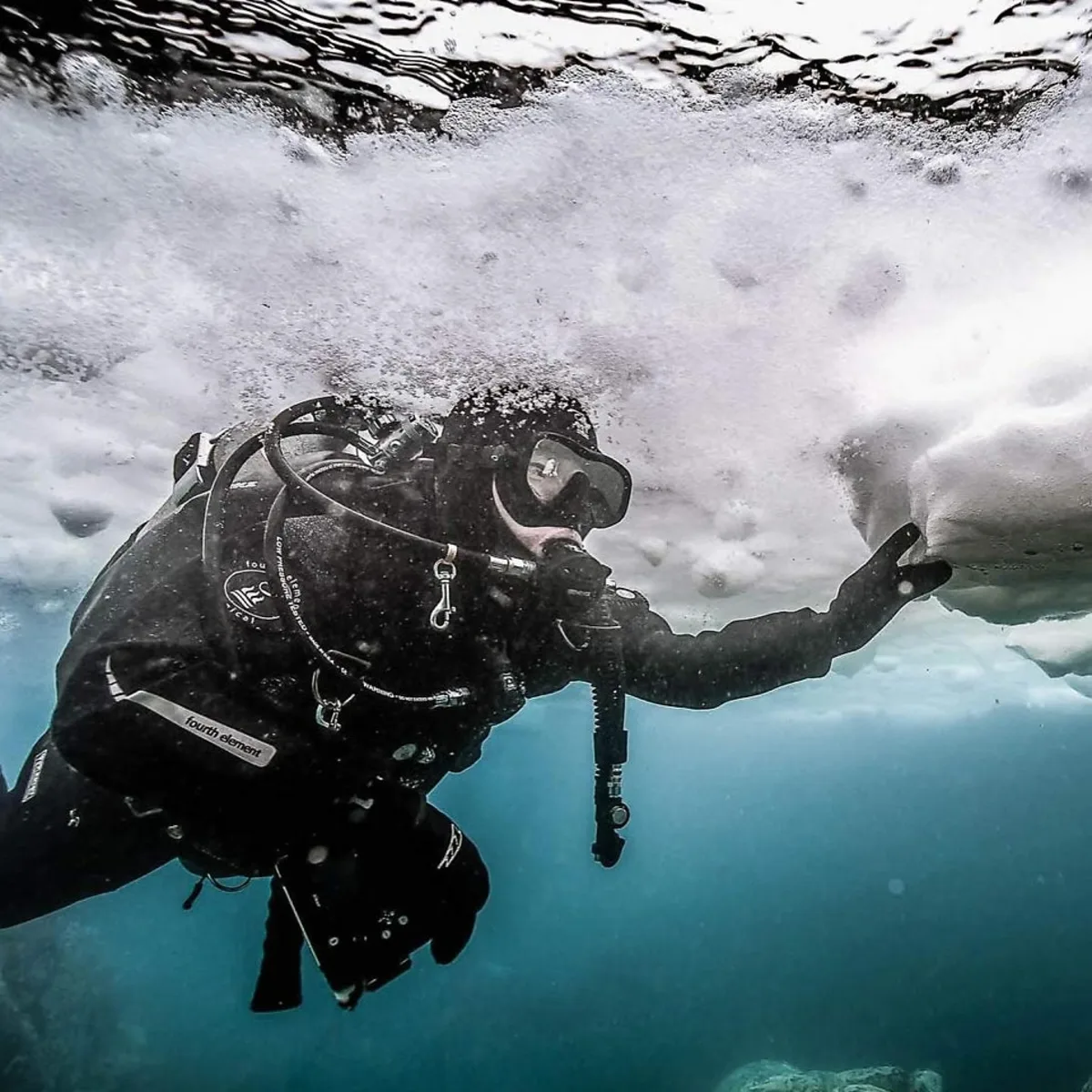 Drysuit diver holding position under ice with controlled buoyancy, the in-water side of drysuit care