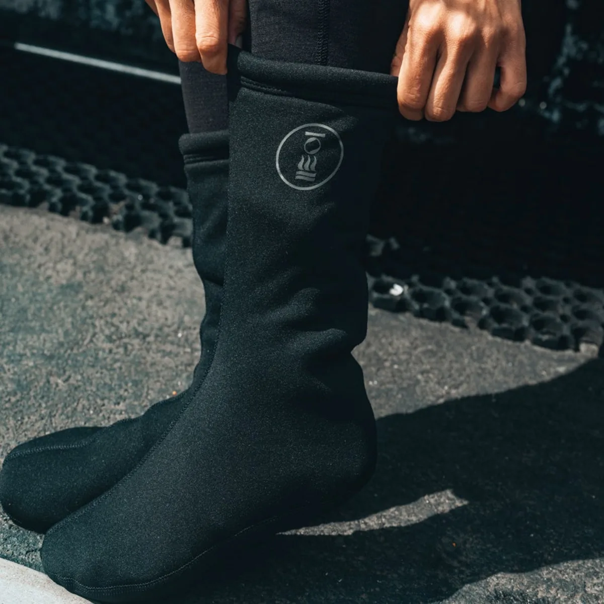 Hands pulling on drysuit socks before a dive, part of the drysuit care routine on shore