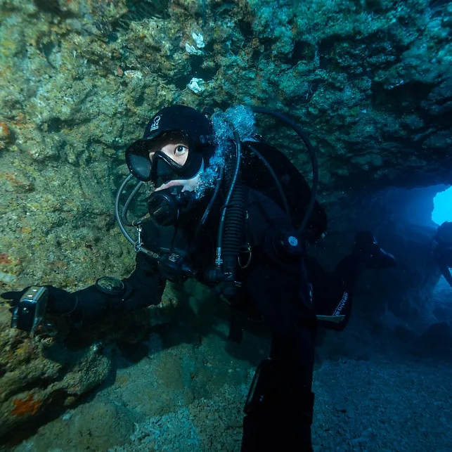 Scuba diver inside an Okinawa cavern looking toward blue open water, Okinawa dive trip for beginners